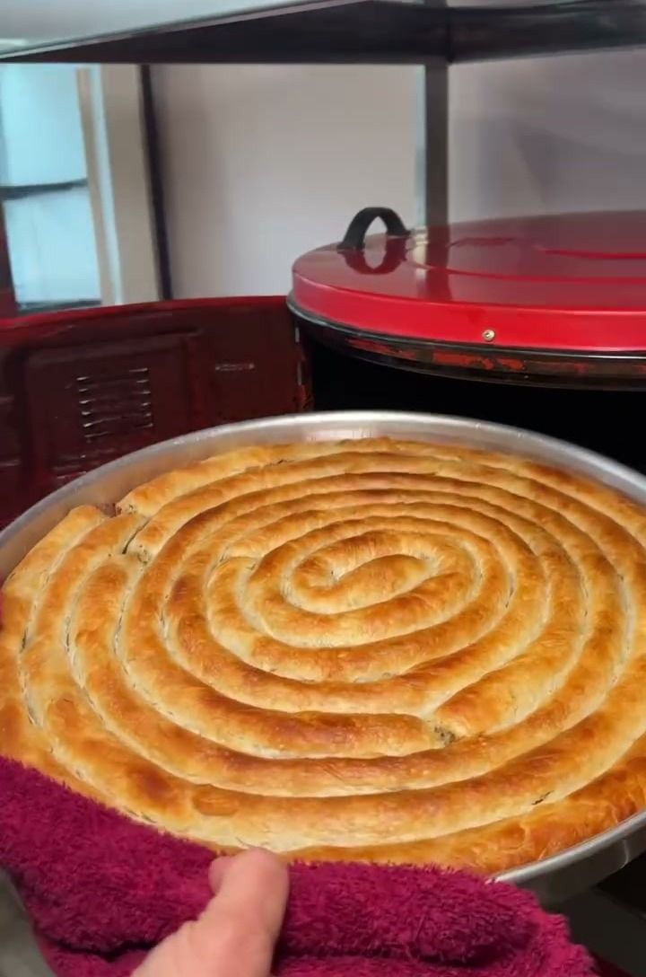 Davul fırından yeni çıkmış, kenarları kızarmış spiral Boşnak böreği tepsisi