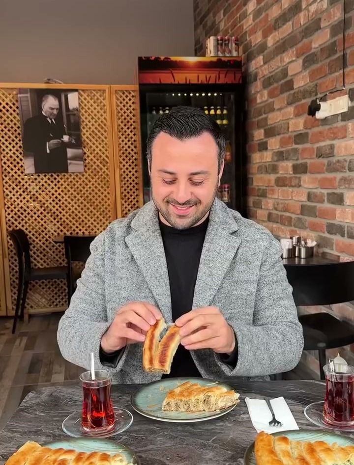 Furuna’da masada çayıyla börek yiyen gülümseyen bir misafir